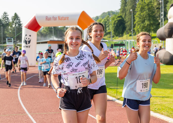 Drei Oberstufenschülerinnen nehmen an einem WWF-Lauf teil und lachen in die Fotokamera.