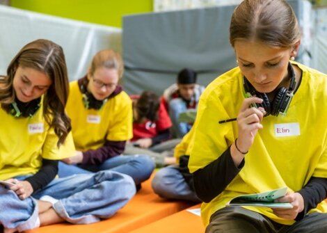 Drei Jugenliche in gelben T-Shirts widmen sich einer Aufgabe, anlässlich des step in to action summits, einem Weiterbildungsprogramm für nachhaltige Bildung.