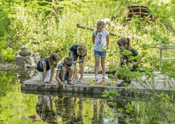 Vier Mädchen spielen im Garten des Naturmuseums. 