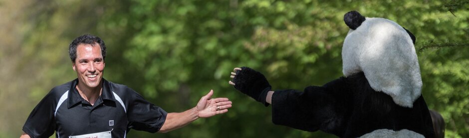 Ein Läufer und das das WWF-Maskottchen geben sich ein High-Five. 